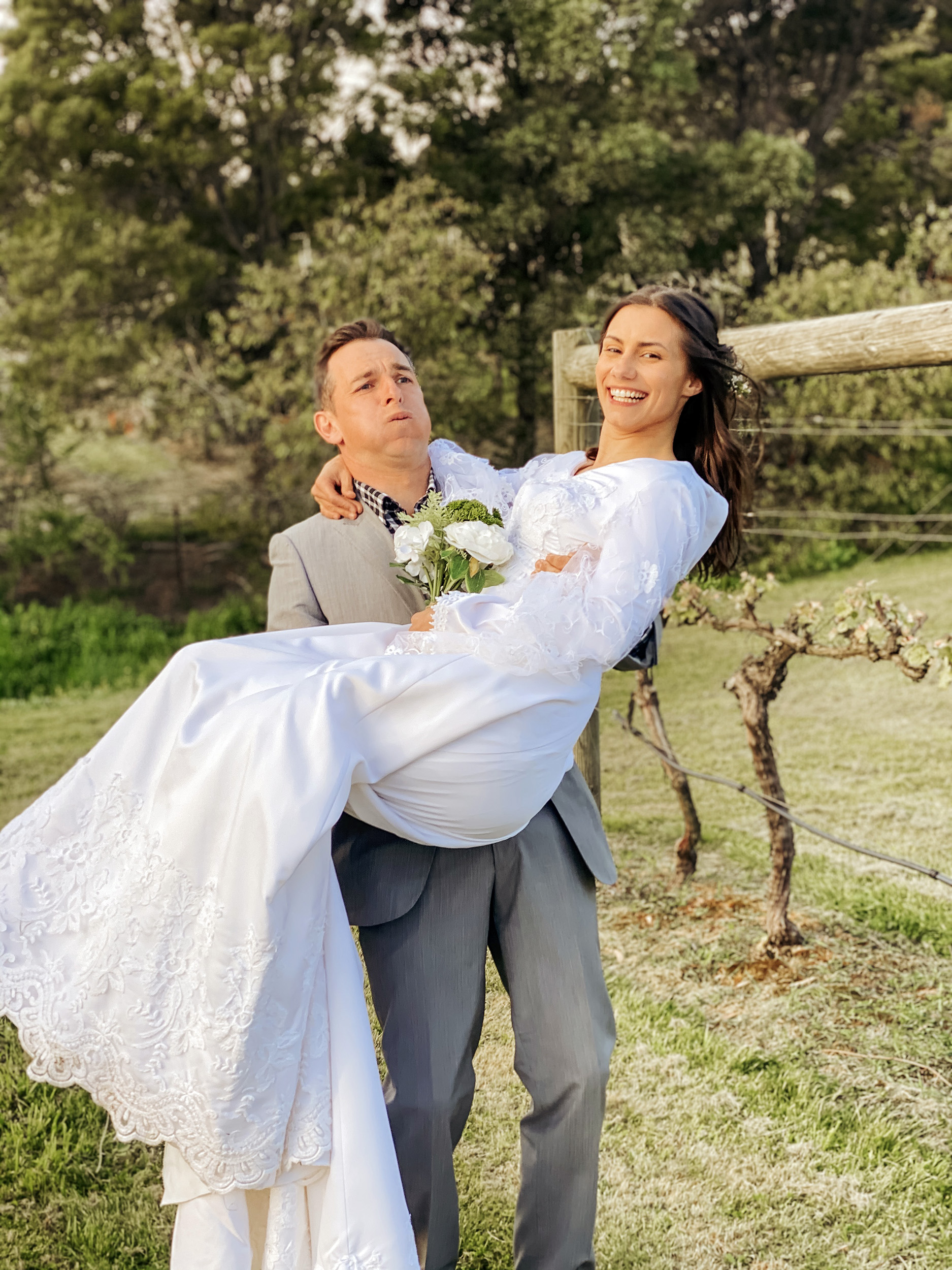 Groom carries bride for their wedding photo in a vineyard near Hobart